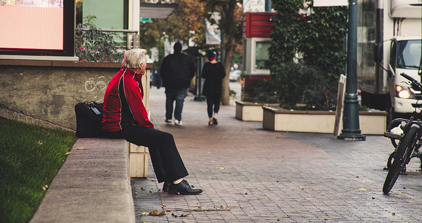 Elderly man sitting in city