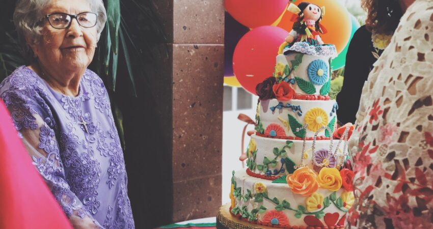 woman wearing purple floral long-sleeved dress besides 4-layer cake